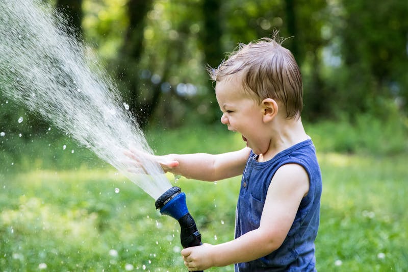 kid playing outside with water